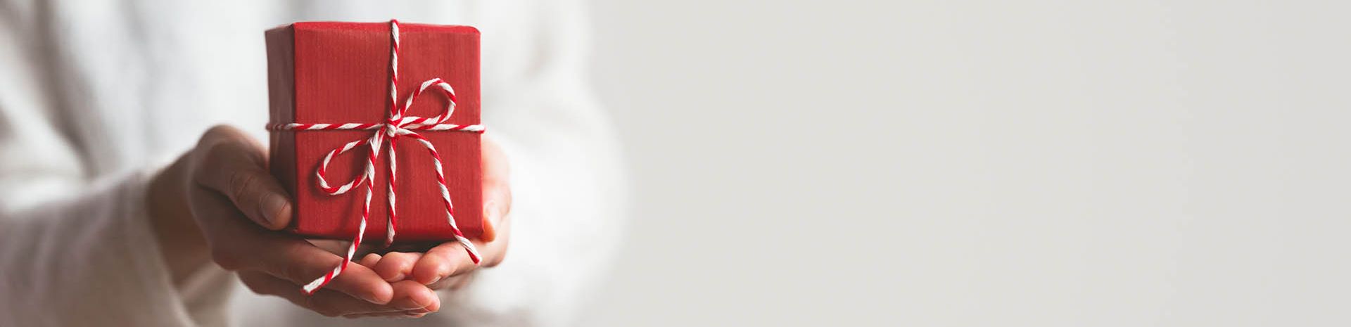 Dans le creux de la main un petit cadeau rouge enroulé d'une ficelle