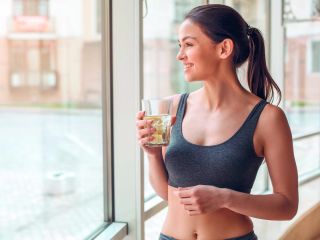 Femme qui tient un verre d'eau pour favoriser l'hydratation