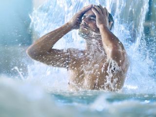 Homme sous une cascade dans la piscine thalasso