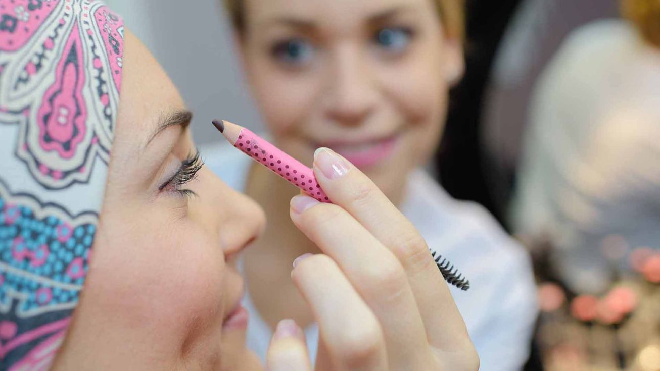 personne appliquant un crayon de maquillage sur un visage