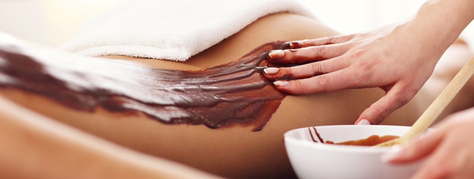Application d'un enveloppement au chocolat sur le dos d'une femme
