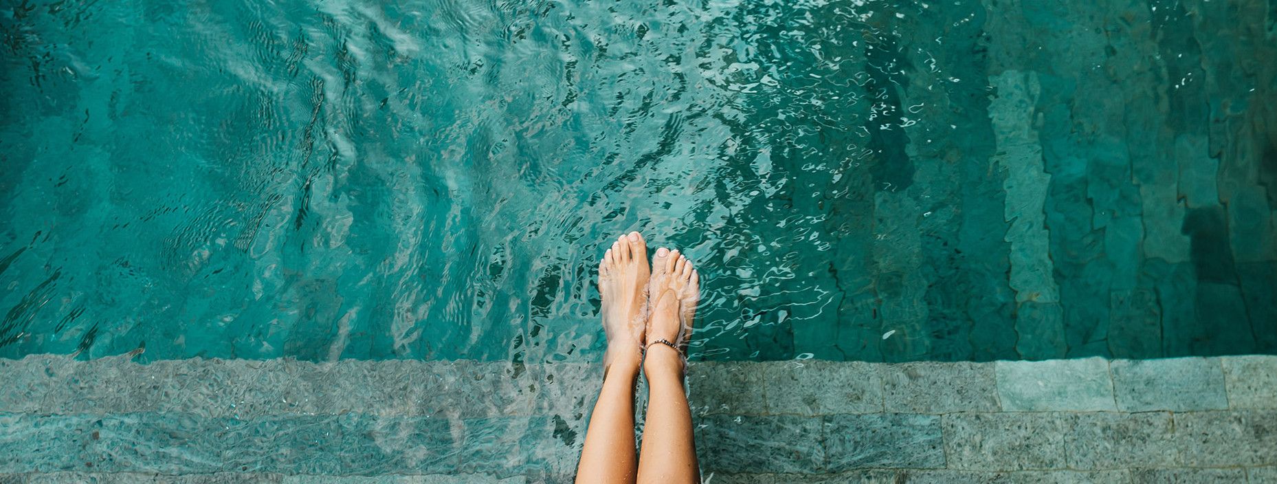Femme au bord de la piscine les pieds dans l'eau