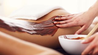 Application d'un enveloppement au chocolat sur le dos d'une femme
