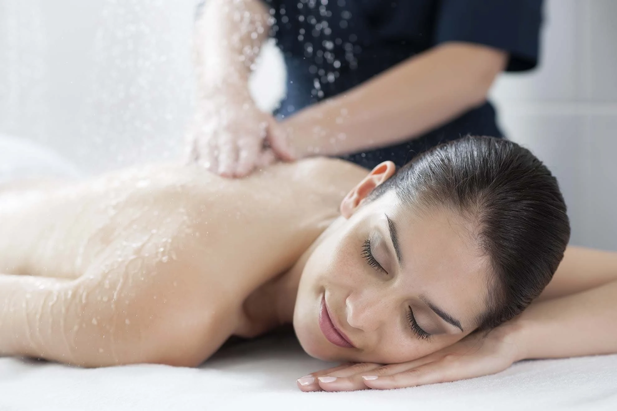 Femme durant un massage sous pluie marine